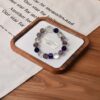 A close-up detail shot of the green rutilated quartz crystal bead on the Bing Fire bracelet.