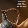 Detail of the sturdy, hand-knotted brown rope carrier and brass bell accessory on the Feng Shui ceramic gourd water bottle.