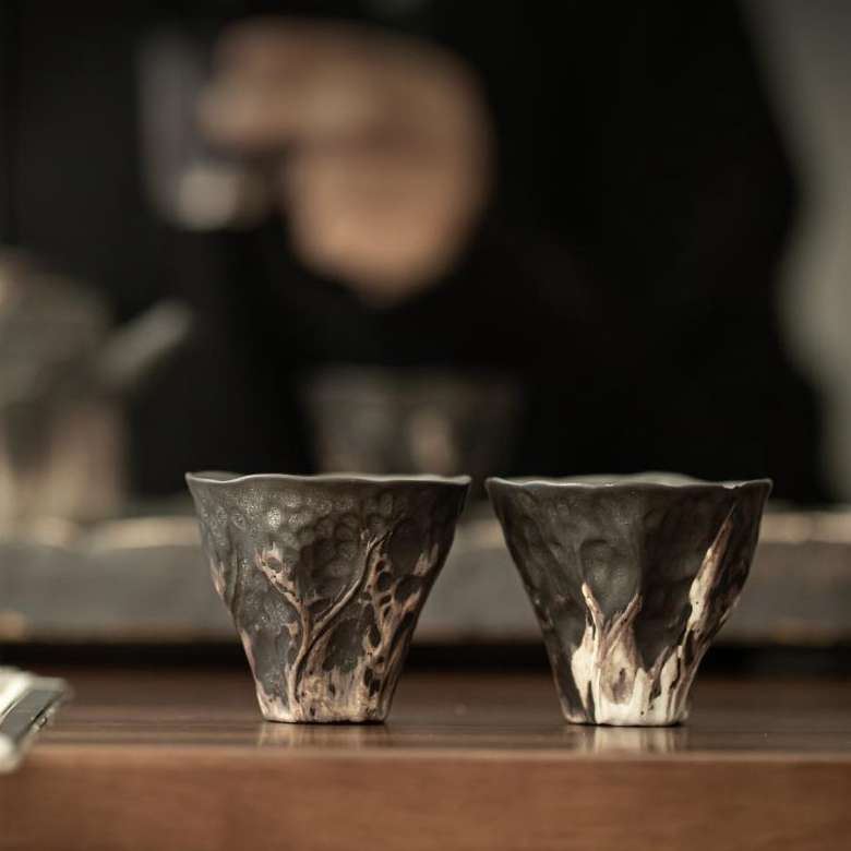 A close-up detail shot of the ornate, silver-accented lid of a handmade ceramic teapot, showing its fine craftsmanship.