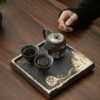 A close-up detail shot of the ornate, silver-accented lid of a handmade ceramic teapot, showing its fine craftsmanship.