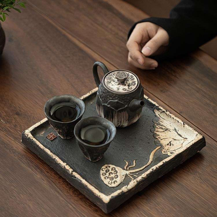 A close-up detail shot of the ornate, silver-accented lid of a handmade ceramic teapot, showing its fine craftsmanship.