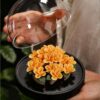 A hand holding the peony flower ceramic diffuser to show its scale and size for placement in any room.