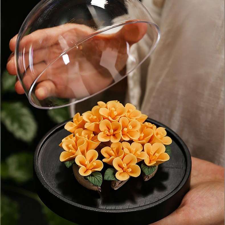 A hand holding the peony flower ceramic diffuser to show its scale and size for placement in any room.