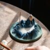 The mesmerizing smoke waterfall effect of the backflow incense burner, with thick, milky smoke pooling in the valleys of the mountain design.