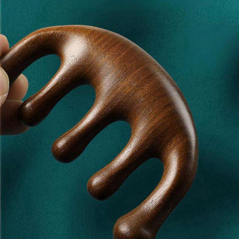 An elegant, dark green sandalwood scalp massager comb with wide, rounded teeth, resting on a clean, neutral background.