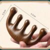 The sandalwood massage comb placed next to a smartphone to provide a clear visual comparison of its size.