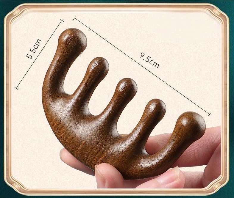 The sandalwood massage comb placed next to a smartphone to provide a clear visual comparison of its size.