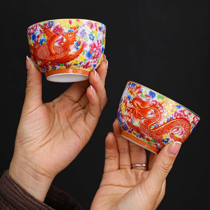 A person enjoying a Gongfu tea ceremony, pouring tea into an exquisite enameled handmade ceramic teacup.