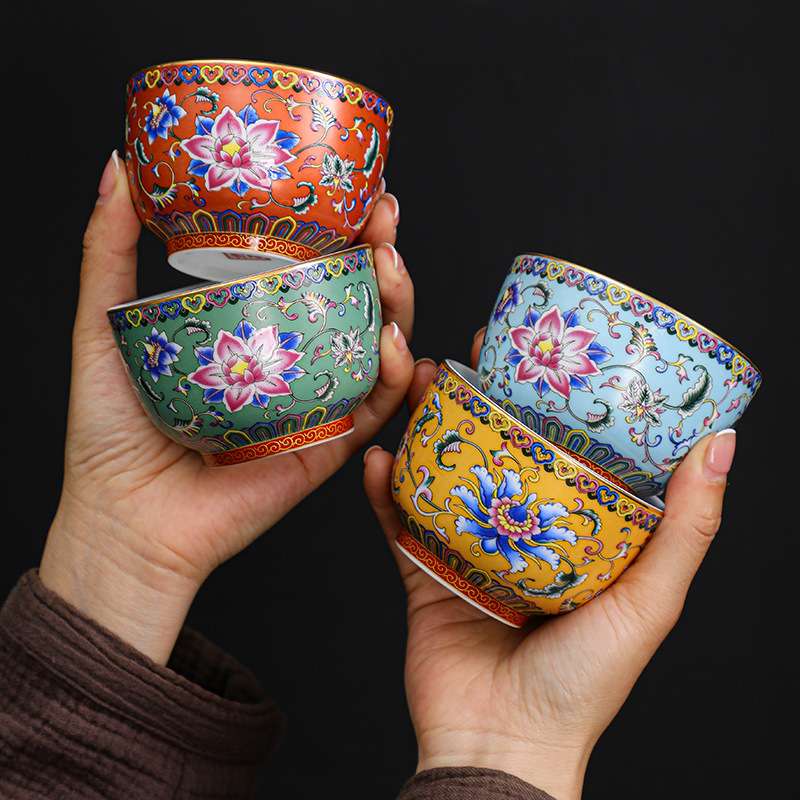 A person enjoying a Gongfu tea ceremony, pouring tea into an exquisite enameled handmade ceramic teacup.