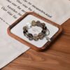 A close-up detail shot of the green rutilated quartz crystal bead on the Wu Earthd bracelet.