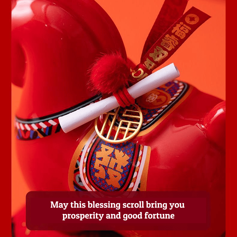 Close up of a red year of the horse ceramic ornament showing the golden coin detail, greeting scroll, and glossy porcelain finish for Lunar New Year decoration.