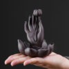 Close up of the smoke waterfall effect flowing down the Buddha hand backflow incense burner from a lit cone.
